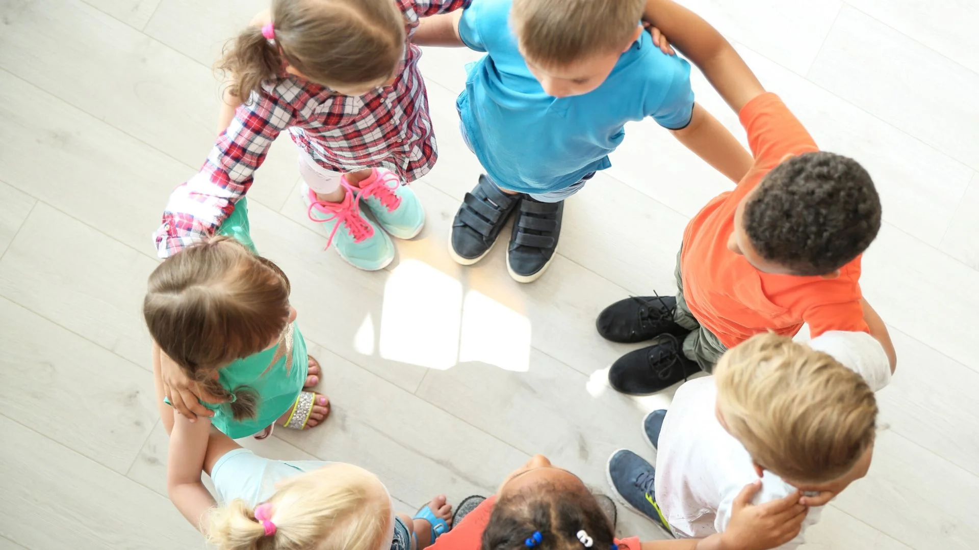 image: group of young children joining circle with their arms