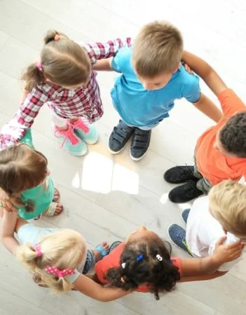 image: group of young children joining circle with their arms