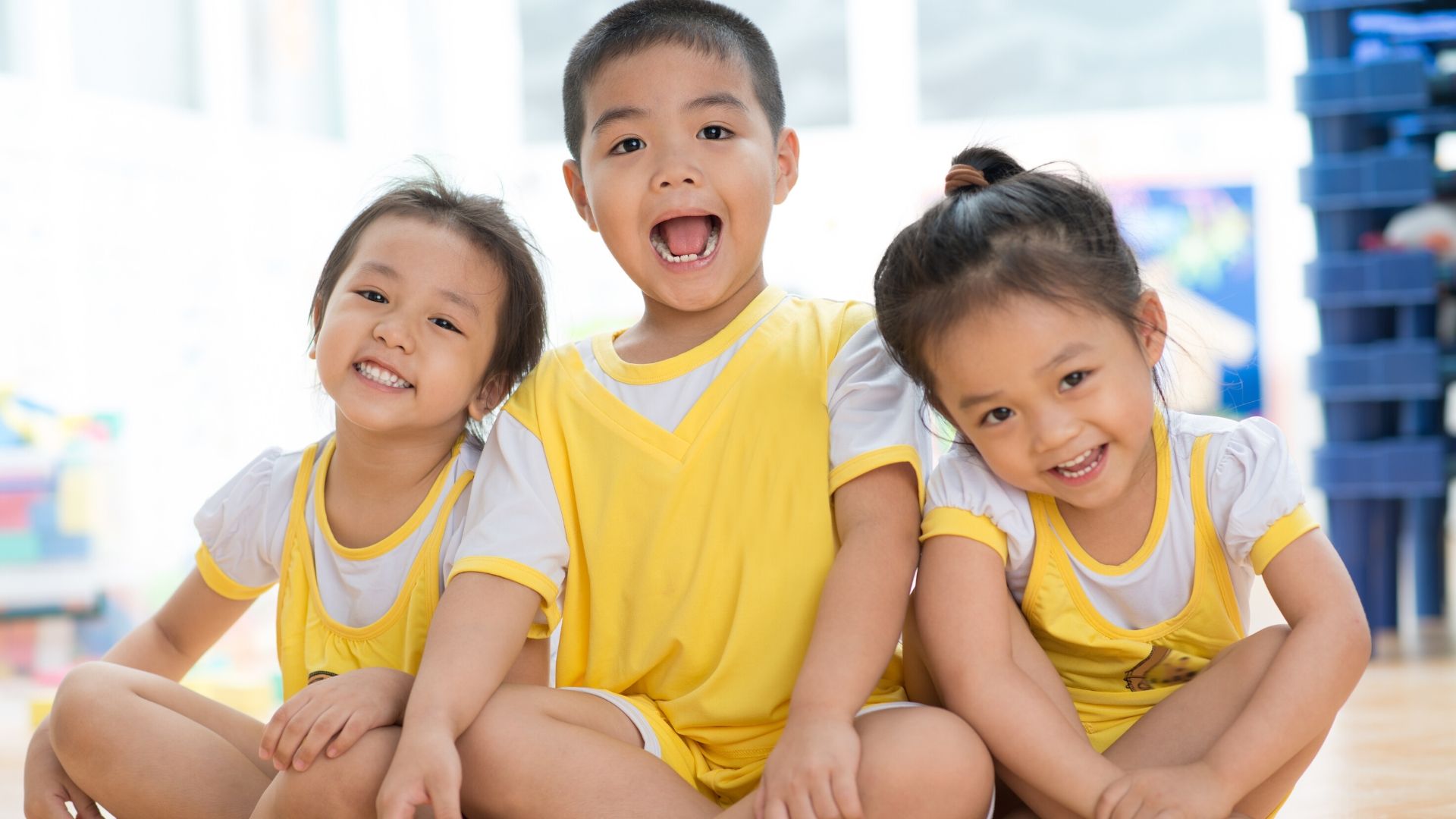 Image: Three asian siblings wearing matching yellow outfits