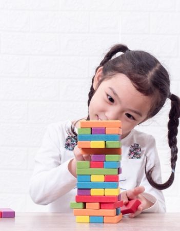 Young asian girl with pigtails playing a wooden blocks game